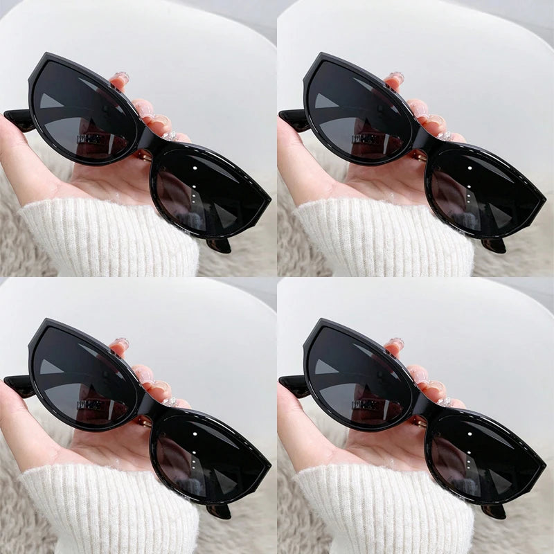 Black cat-eye sunglasses held in a hand, showcasing a glossy finish and sharp, upswept design.
