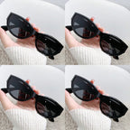 Black cat-eye sunglasses held in a hand, showcasing a glossy finish and sharp, upswept design.