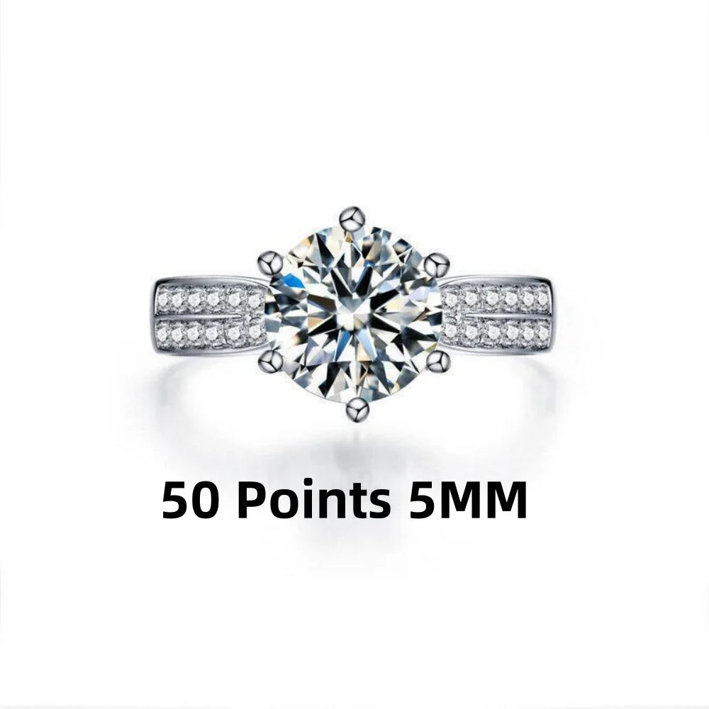Round-cut Moissanite stone in a 925 sterling silver band, accented by smaller stones on the sides, showcasing high polish.