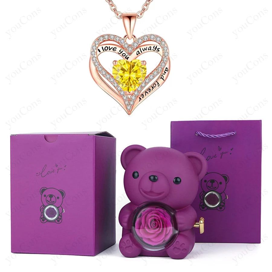 Heart-shaped pendant necklace with a yellow gem, surrounded by clear stones, in a luxury purple gift box with a teddy bear and preserved rose.