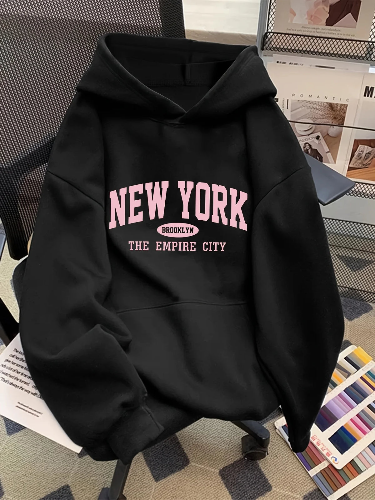 Black oversized hoodie featuring a pink "NEW YORK" graphic, kangaroo pocket, and soft fleece material.