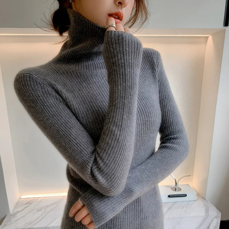 Slim-fit turtleneck in soft gray cashmere, featuring ribbed texture and extended sleeves, styled elegantly with a high neck.