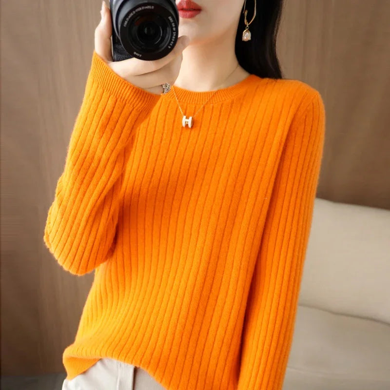 Cozy orange ribbed pullover with a crew neck, featuring long sleeves and a relaxed fit, presented by a model holding a camera.