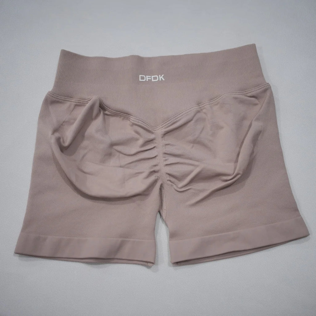High-waisted gym shorts in soft beige with a scrunch-butt design, seamless fabric, and a wide elastic waistband.