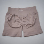 High-waisted gym shorts in soft beige with a scrunch-butt design, seamless fabric, and a wide elastic waistband.