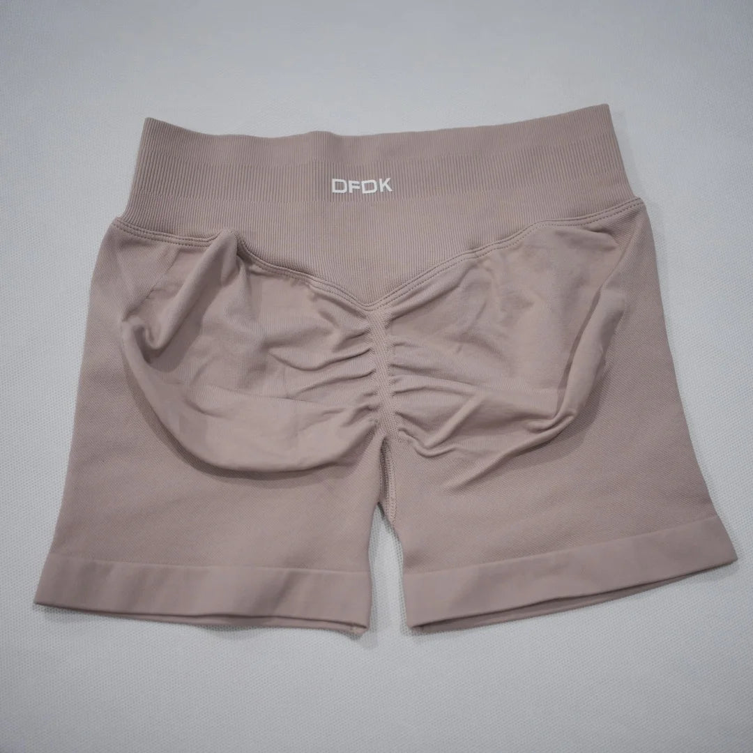 High-waisted gym shorts in soft beige with a scrunch-butt design, seamless fabric, and a wide elastic waistband.