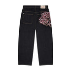 Baggy distressed denim jeans in dark wash with pink embroidered floral detail on the back pocket and relaxed wide-leg cut.