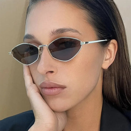 Polygonal metal sunglasses with diamond-cut lenses, sleek metallic temples, worn by a model with a casual, confident pose.