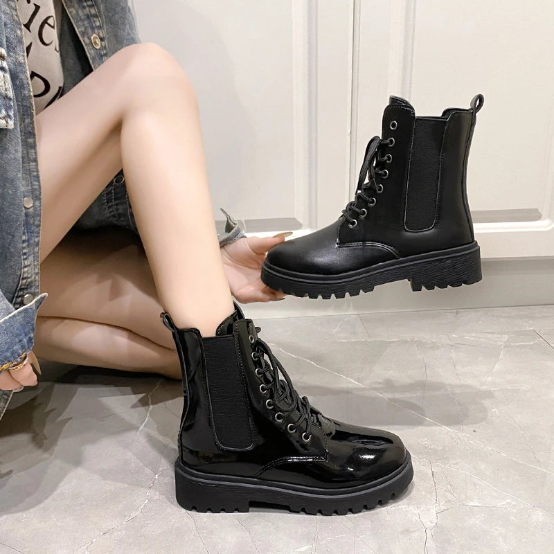 Black croc-embossed Chelsea boots with a chunky platform, featuring lace-up front and elastic side panels, shown on a model's feet.