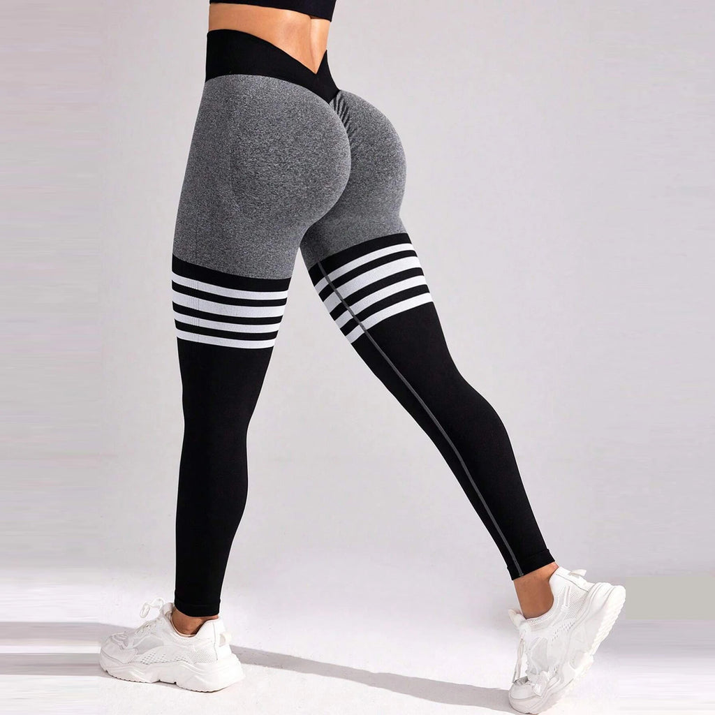 High-rise black and gray seamless leggings with varsity stripes, featuring a deep V-back design and a fitted silhouette.
