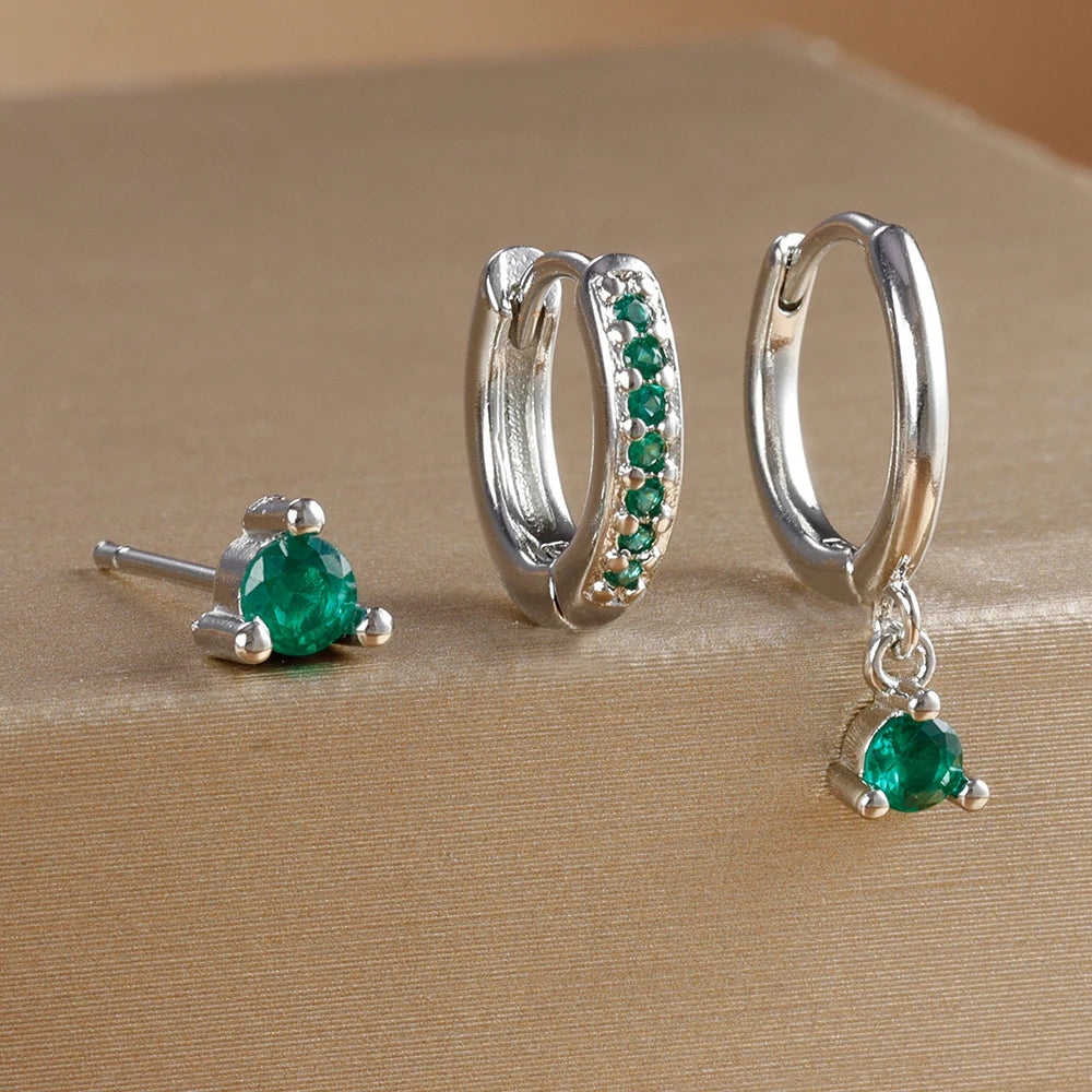 Three-piece earring set featuring a green gemstone stud, a embellished hoop, and a dangling earring, all in silver tones.