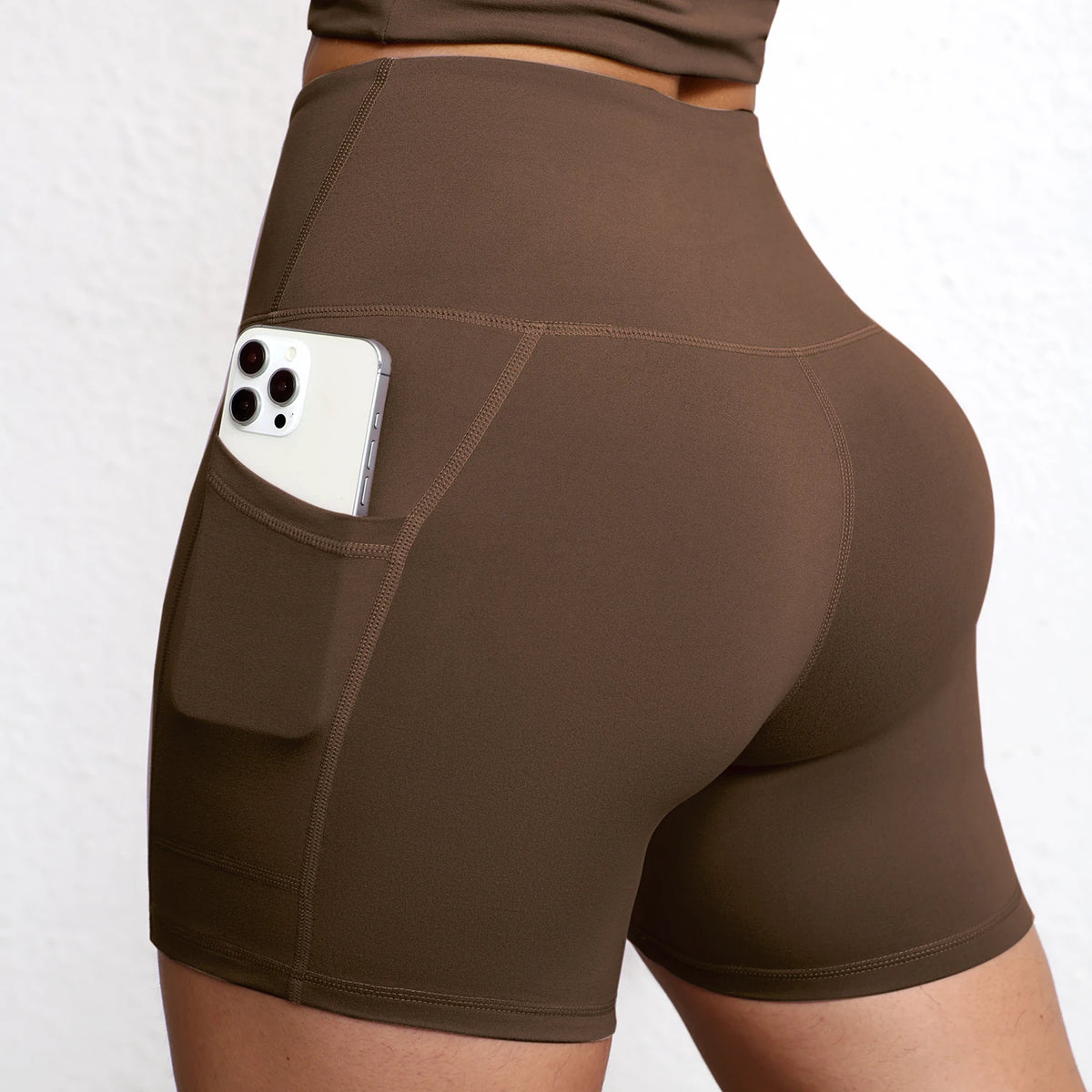 High-waisted seamless yoga shorts in brown with a side pocket for a smartphone, featuring a body-sculpting design.