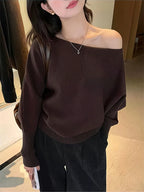 Off-shoulder brown pullover with batwing sleeves and a relaxed fit, paired with loose black pants.