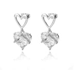 Chunky huggie earrings with heart-shaped drop, featuring clear crystals and a shiny silver-tone finish.