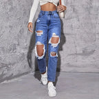 High-waisted distressed straight-leg denim jeans in light blue, featuring large rips, paired with a fitted crop top and white sneakers.