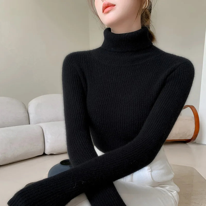 Black ribbed slim-fit turtleneck sweater with high collar, worn by a model with long sleeves, styled casually with light bottoms.