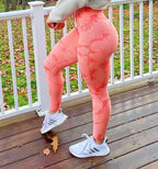 High-waisted seamless leggings in a peachy pink with contour shading, paired with white athletic sneakers.