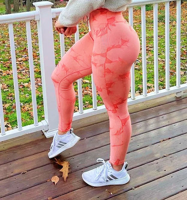 High-waisted seamless leggings in a peachy pink with contour shading, paired with white athletic sneakers.