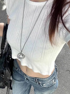 Baggy denim cargo jeans in light blue with a wide-leg silhouette, paired with a white cropped top and silver pendant necklace.