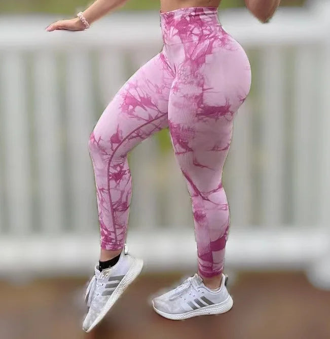 High-waisted pink marbled leggings with contouring details, worn with white athletic shoes.