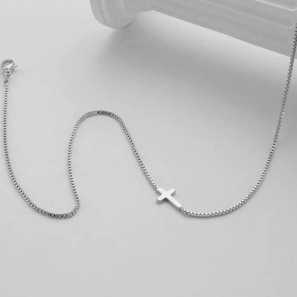 Minimalist high-polish mini cross necklace on a sleek chain, crafted from stainless steel in silver.