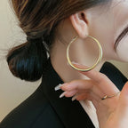 Gold chunky hoop earrings displayed on a model with a low bun, accentuating their high-gloss finish and minimalist design.