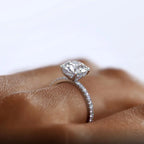 A sparkling 2-carat round-cut Moissanite solitaire ring with a six-prong setting, featuring a silver band adorned with smaller stones.