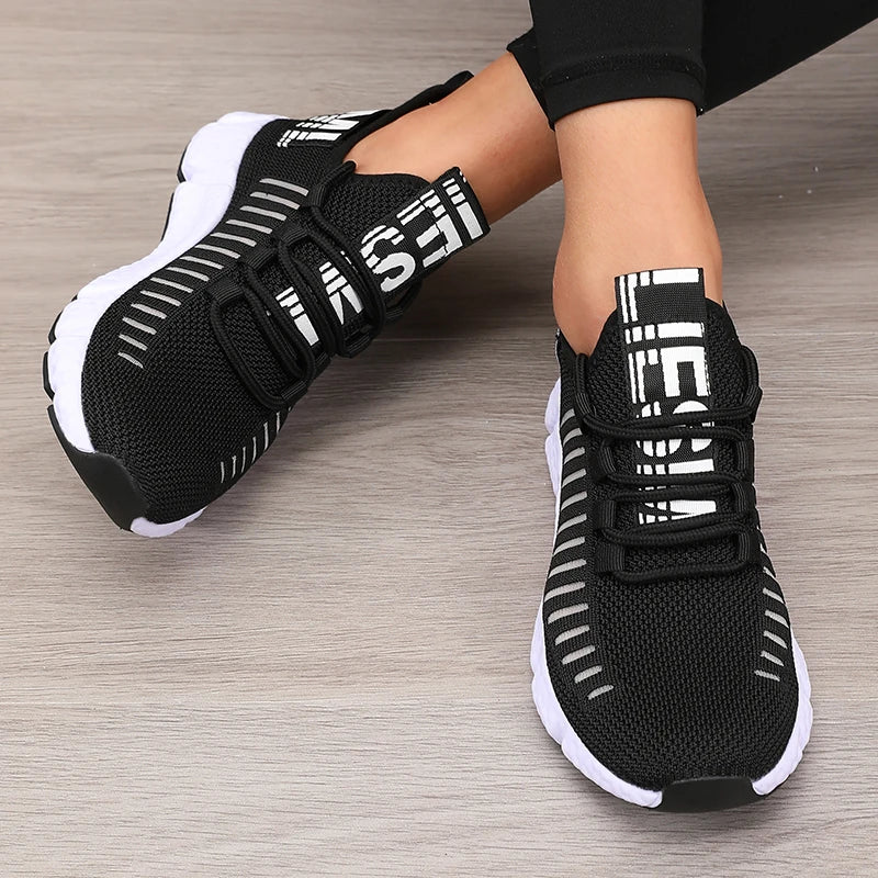 Black knitted performance sneakers with a lace-up design, featuring white accents and a flexible rubber sole.