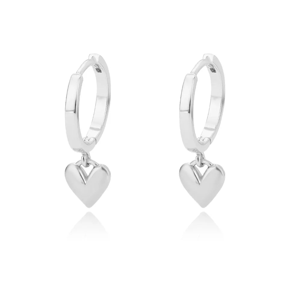 Chunky huggie earrings in polished stainless steel, featuring a dangling heart charm for a minimalist, modern look.