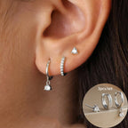 Three-piece earring set features a sparkly drop earring, a crystal-studded hoop, and a minimalist stud, all in stainless steel.