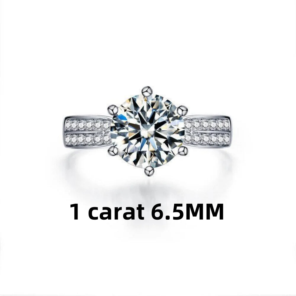 Round-cut moissanite stone set in a high-polish 925 sterling silver band with accent stones on the sides.