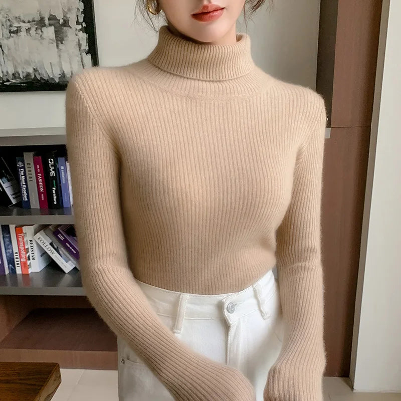 Beige ribbed turtleneck sweater with a slim-fit design and high collar, styled with white pants.