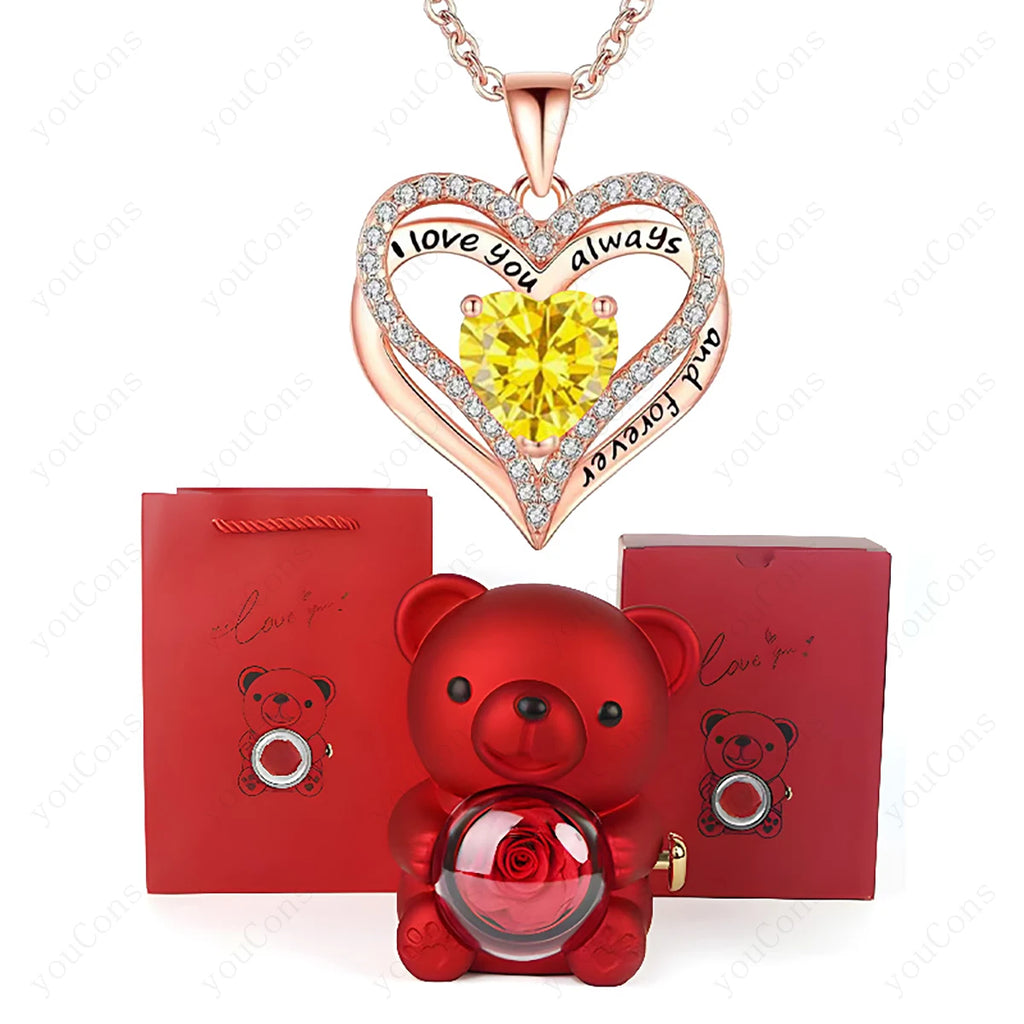 Red heart necklace with a yellow stone, surrounded by diamonds, and a cute red teddy bear holding a rose, all in luxury packaging.