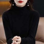 Black turtleneck sweater made from merino wool and cashmere, featuring a relaxed fit and ribbed cuffs, worn with bold earrings.