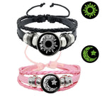 Multi-layered leather bracelet set featuring a black sun design and a pink moon design with braided straps and metal accents.