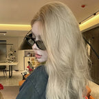 Chunky black cat-eye sunglasses with a glossy finish, worn by a model with long, wavy blonde hair.