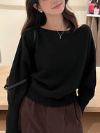 Black off-shoulder batwing pullover with relaxed long sleeves, ribbed cuffs, and a cozy fit, worn with high-waisted pants.