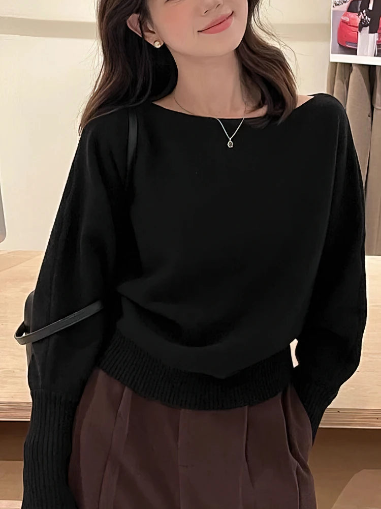 Black off-shoulder batwing pullover with relaxed long sleeves, ribbed cuffs, and a cozy fit, worn with high-waisted pants.