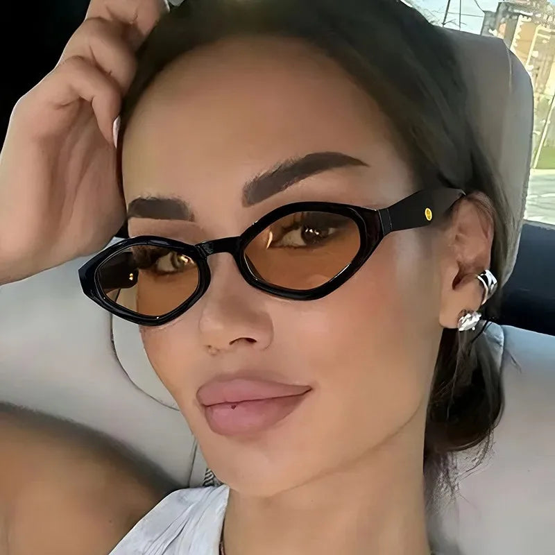 Bold cat-eye sunglasses with a black frame and brown tinted lenses, worn stylishly by a model.