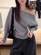 Gray LOVORA™ Off-Shoulder Batwing Knit Pullover with relaxed sleeves, styled with black pants and a handbag.